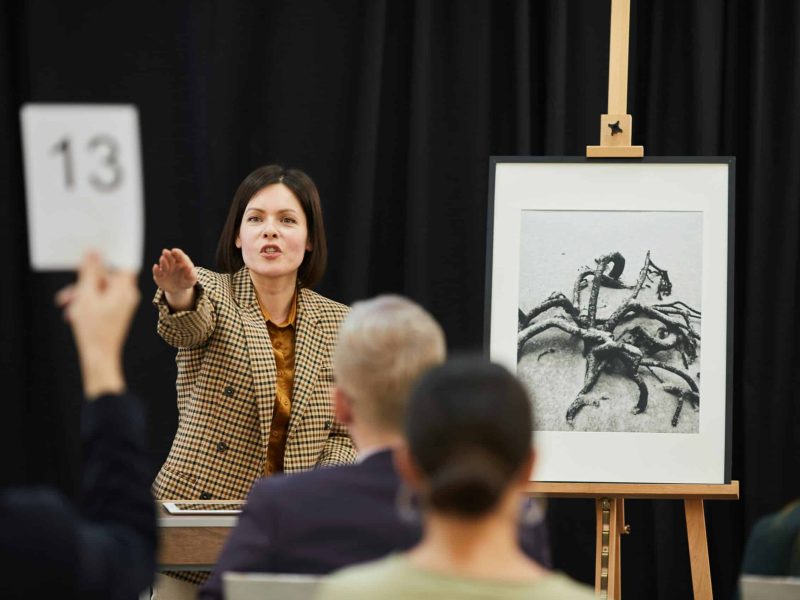 Auctioneer pointing to an audience member bidding on an artwork